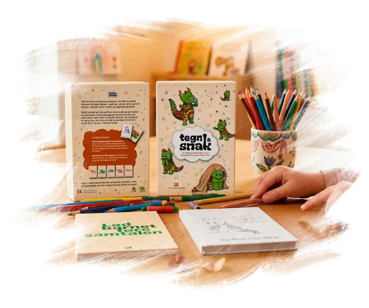 Et produktbillede af produktet Tegn og Snak, hvor man kan se produktæsken, dens indhold samt en lille piges hånd, der holder farveblyanter