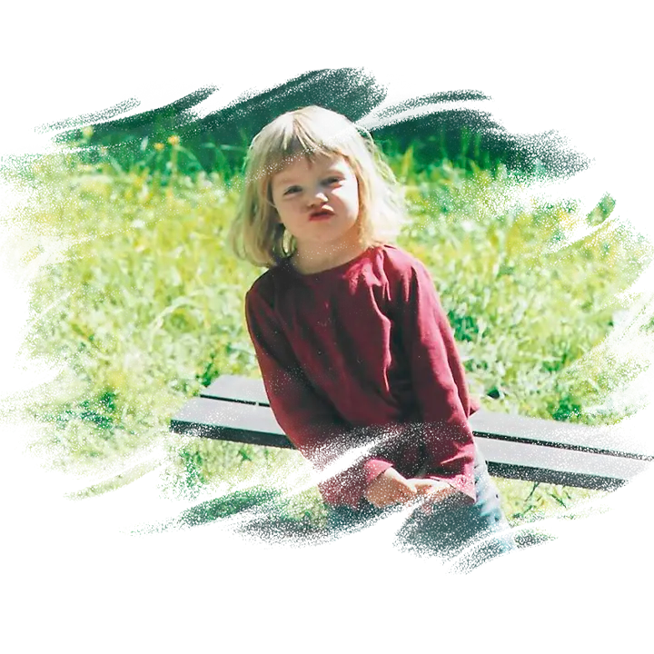 Pige på fem år står på græsset og kigger ind i kamera.