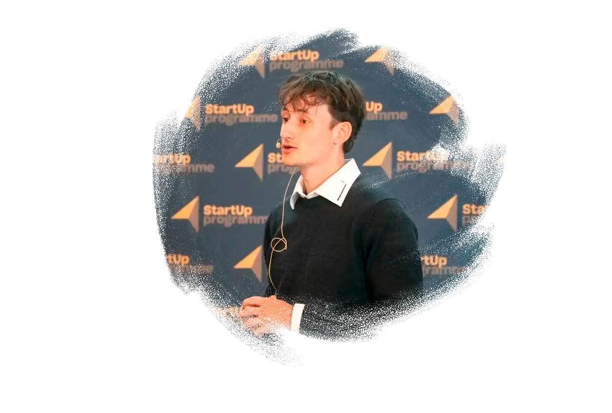 Ung mand med mikrofon står og præsentere.