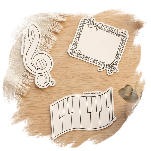 Tre store klistermærker som ligger på et bord. Viser en g-nøgle, et klaver og en ramme.